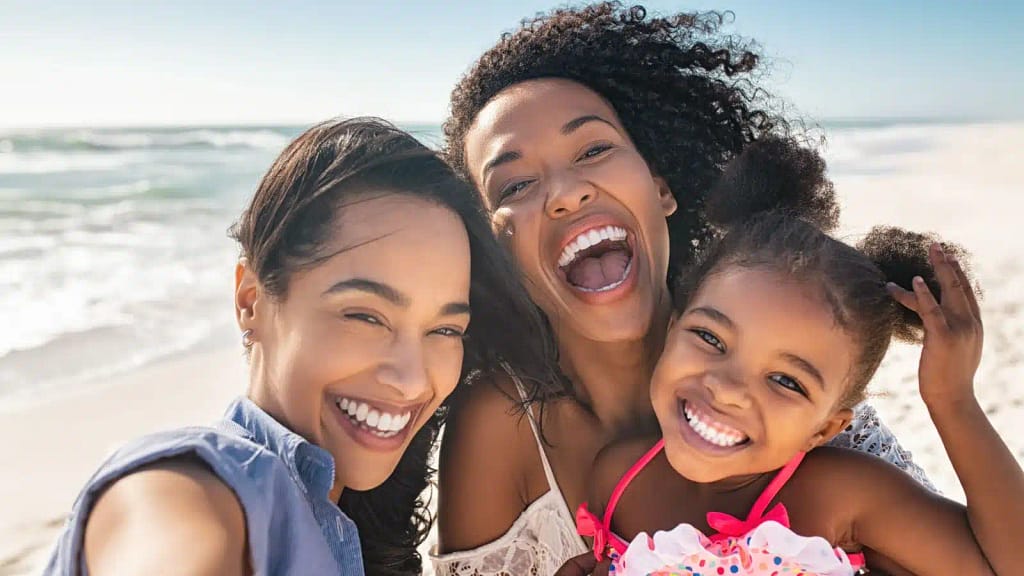 A lesbian couple take a selfie with their daughter at the beach