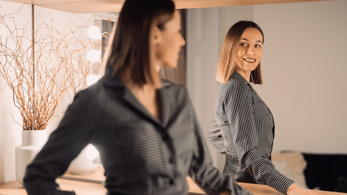 A confident woman standing in front of a mirror.