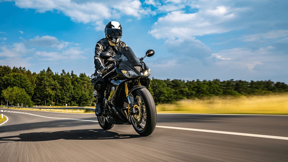 Someone riding a motorcycle on a road against a blue sky.