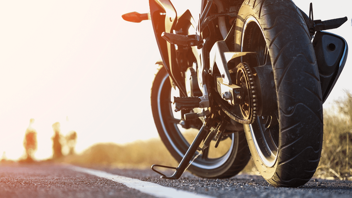 A motorcycle driving down a road at sunset.