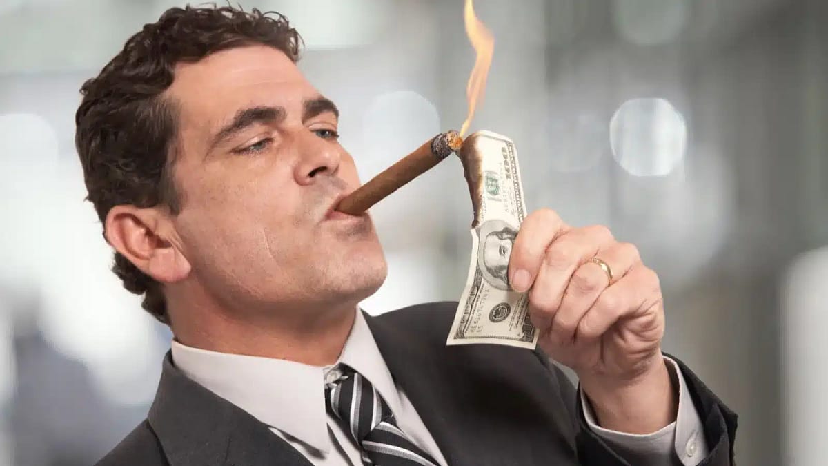 Rich investor guy lights a cigar with $100 bill