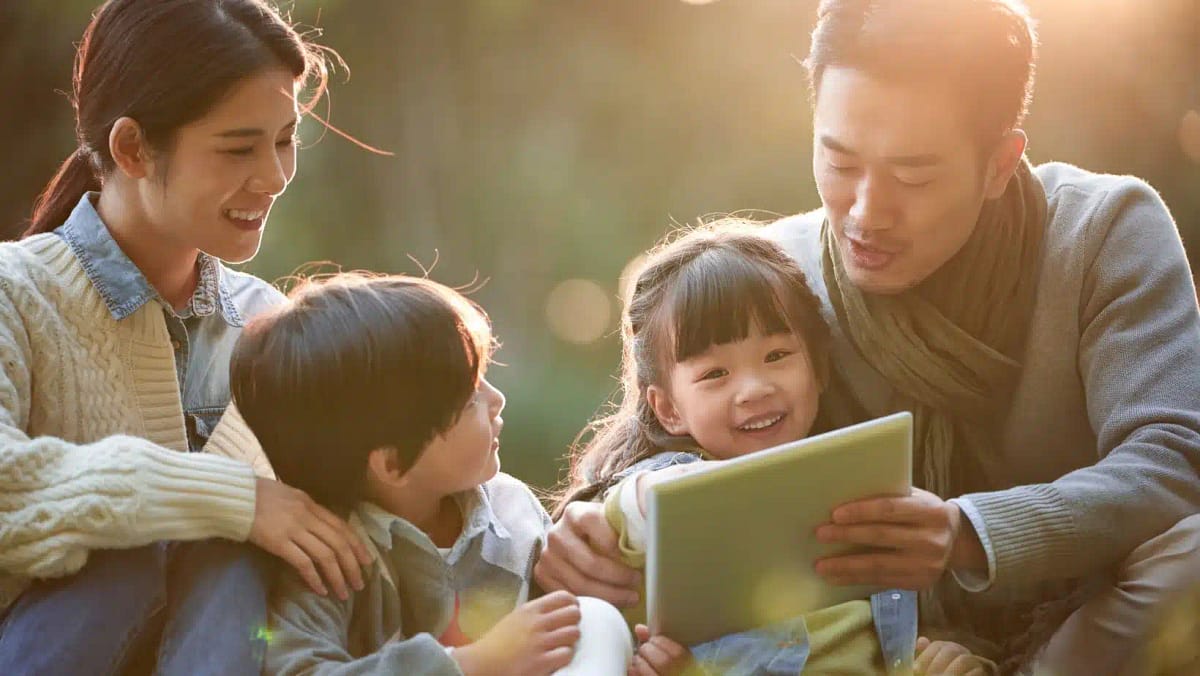 young Asian parents show their children something on a tablet