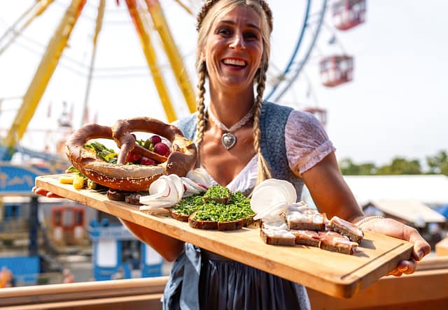 Happy Woman In Traditional Bavarian Dress Serving A Variety Of