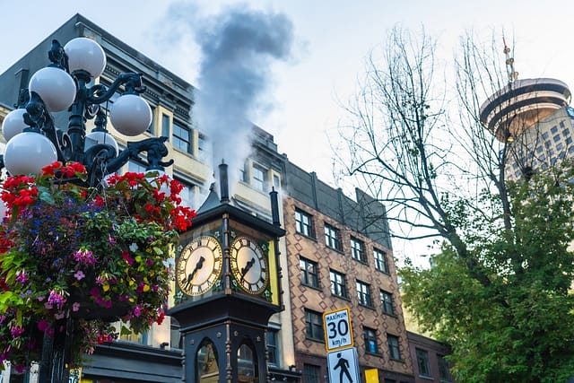 Gastown Steam Clock Releasing Clouds Of Steam Amidst Vibrant Flowers